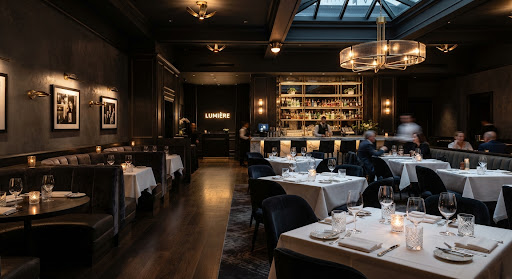 Wide architectural shot of a luxury restaurant interior with charcoal walls and gold fixtures.