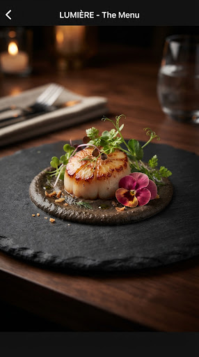 Signature seared scallop dish with microgreens and an edible flower on a dark slate plate.