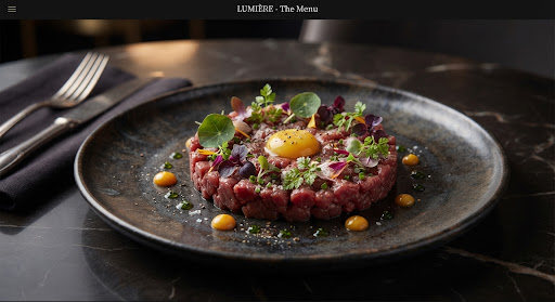 Beef tartare appetizer topped with a raw quail egg yolk and micro herbs.